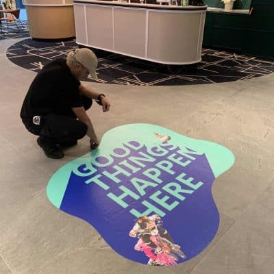 Installing floor graphic in blue rocks foyer